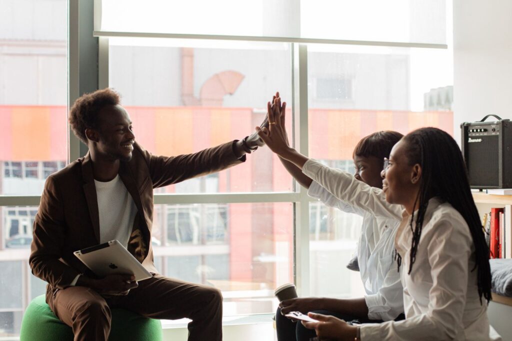 Happy colleagues in a modern office celebrating teamwork success with a high five.